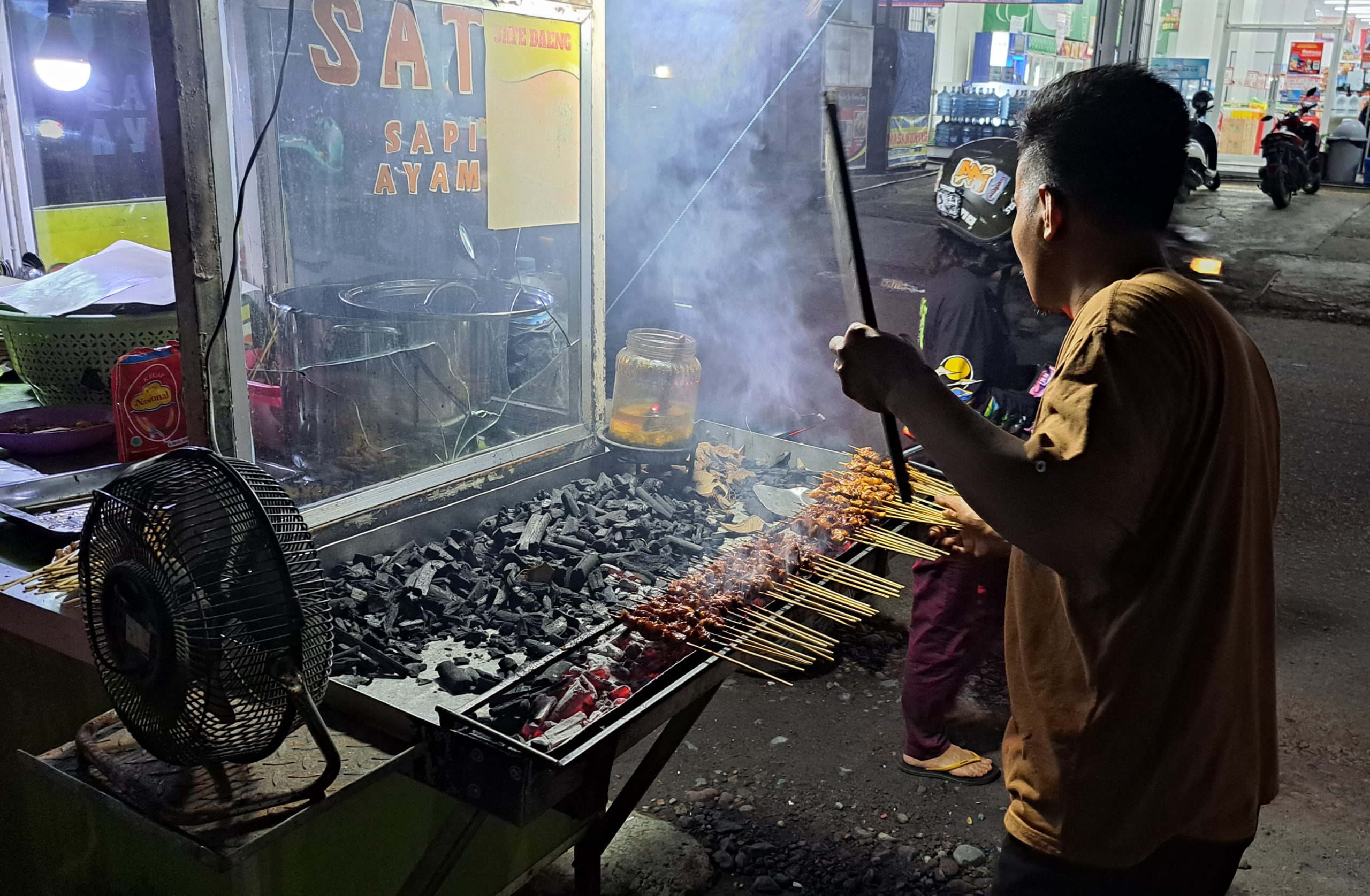 Pedagang sate Makassar, terlihat sedang mengipas sate di atas pembakaran./foto.dunia cerita